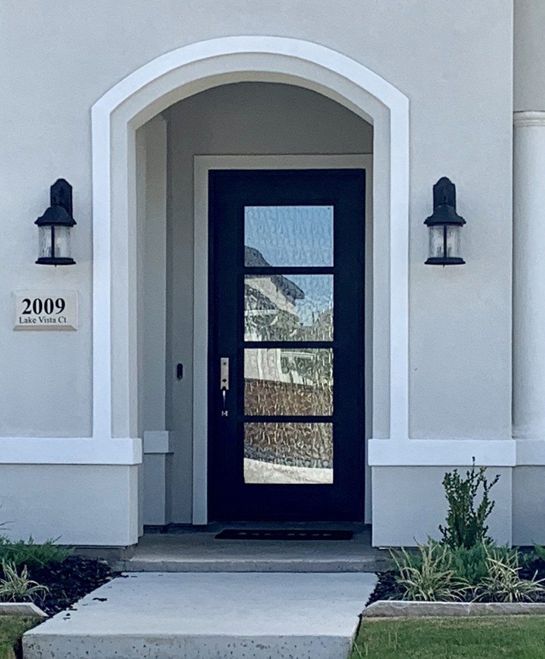 White stucco home with black iron front door