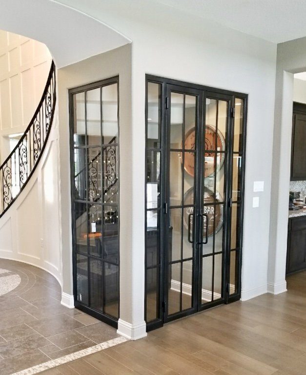 Wine cellar enclosed on three sides by glass and iron doors and windows