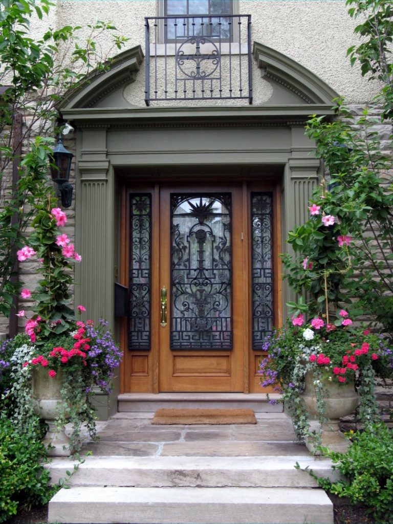 image of a single wrought iron door surrounding by an entryway full of greenery